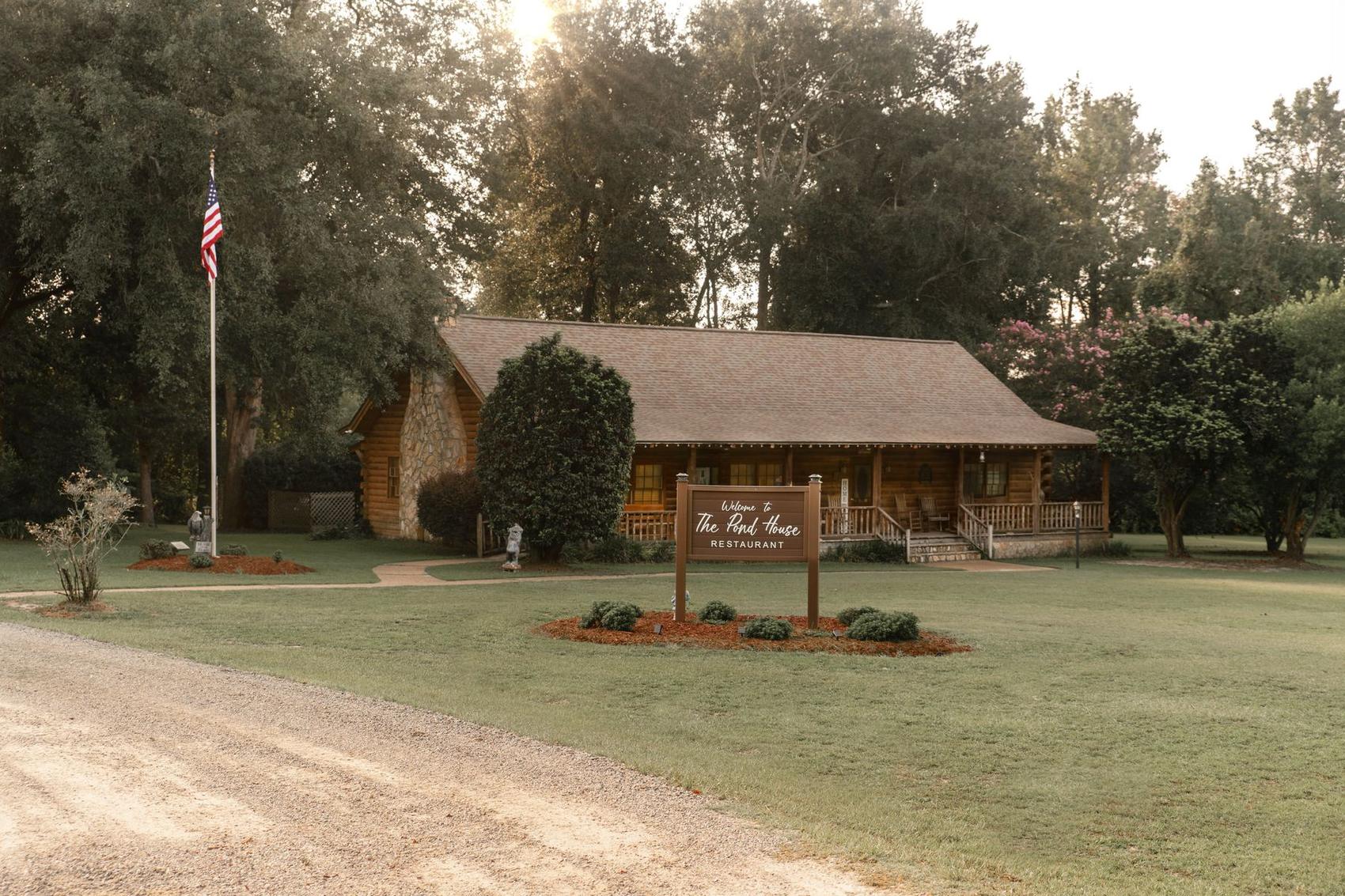 The Pond House Restaurant log cabin at golden hour, flag flying and the welcome sign out front on Bethany Church Road