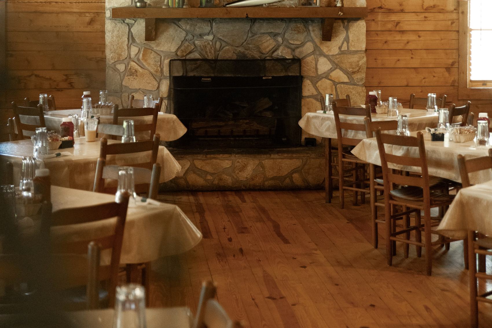 The Pond House dining room with exposed beams, ceiling fans and set tables