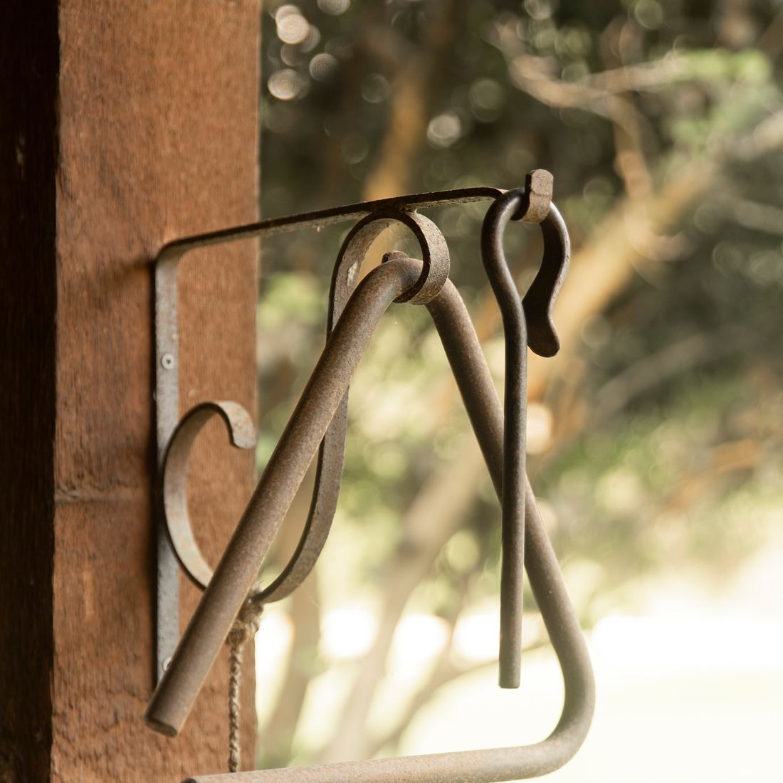 An iron dinner triangle hanging from a post on the cabin porch