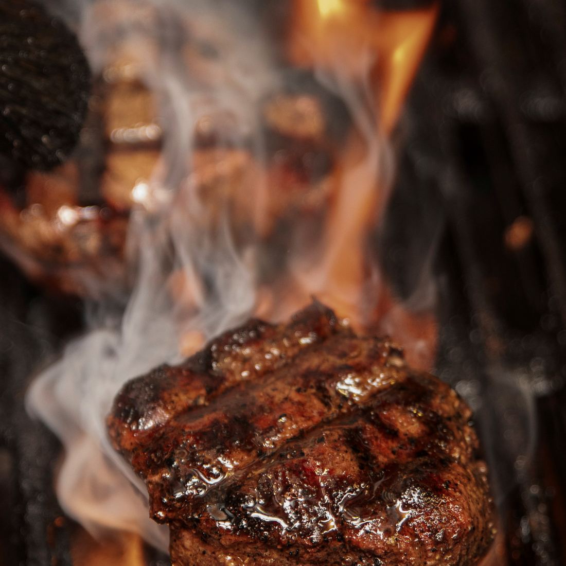 A steak searing over open flame on the charbroiler